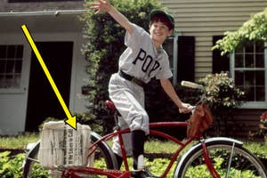 Child in a baseball uniform delivering newspapers on a bike, waving, with papers in a front basket