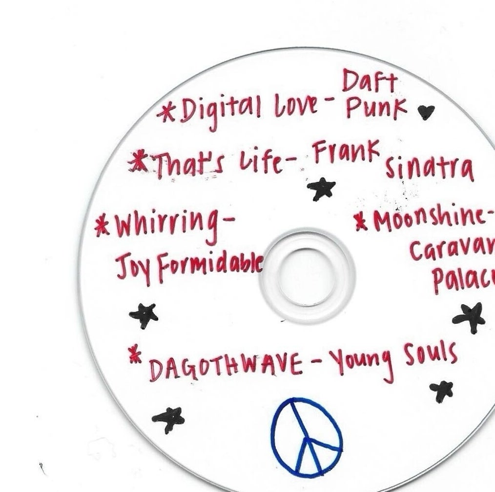 Handwritten list of songs with artists on a CD, including &quot;Digital Love&quot; by Daft Punk, decorated with stars and a peace sign