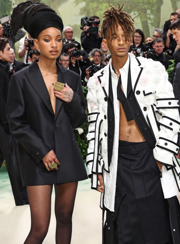 Willow and Jaden Smith dressed in avant-garde outfits, one in an oversized blazer and the other in a layered ensemble with buckles