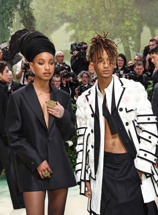Willow and Jaden Smith dressed in avant-garde outfits, one in an oversized blazer and the other in a layered ensemble with buckles
