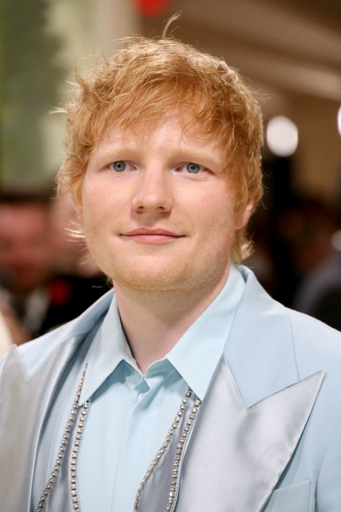 Ed Sheeran in a light blue suit with a silver necklace at an event