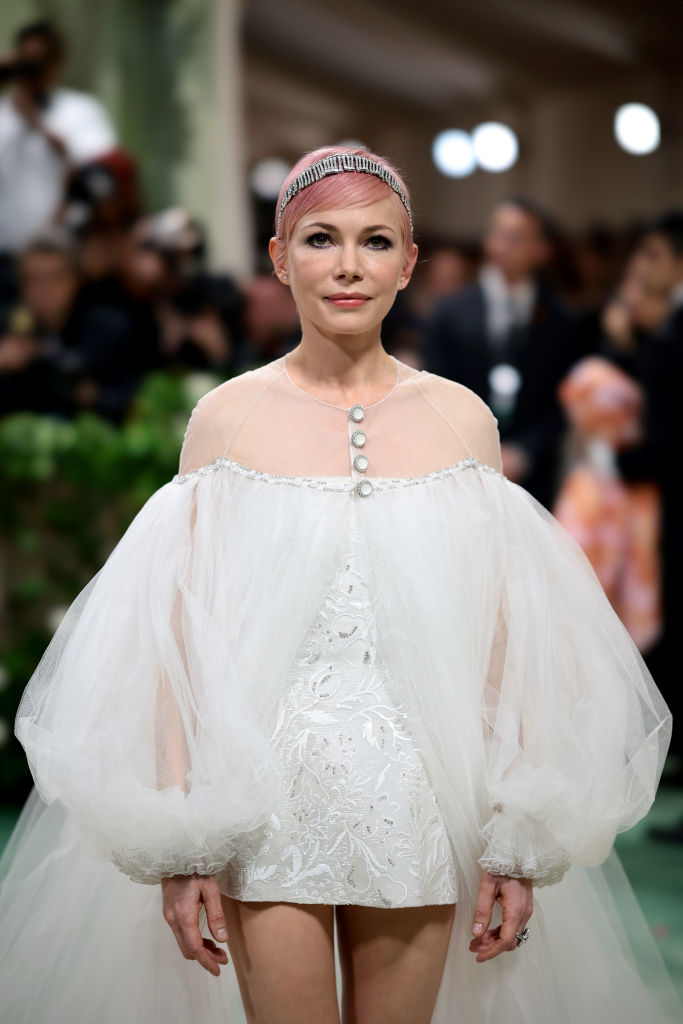 Michelle Williams on red carpet in sheer, embroidered white outfit with puffy sleeves