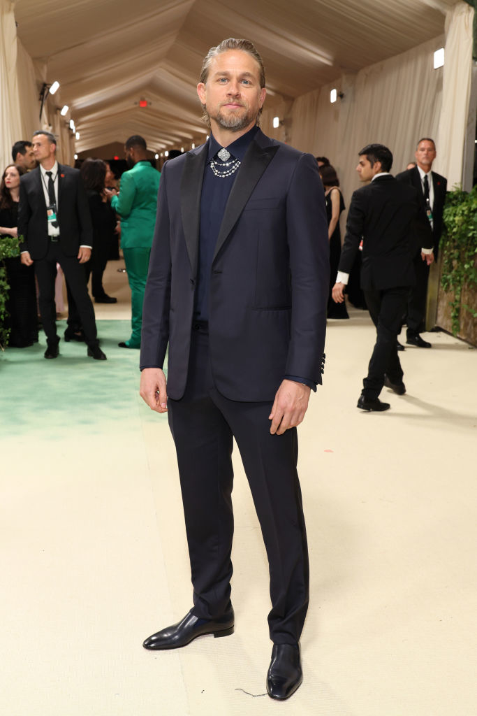 Charlie in a tailored suit with embellished lapels and a statement necklace at an event