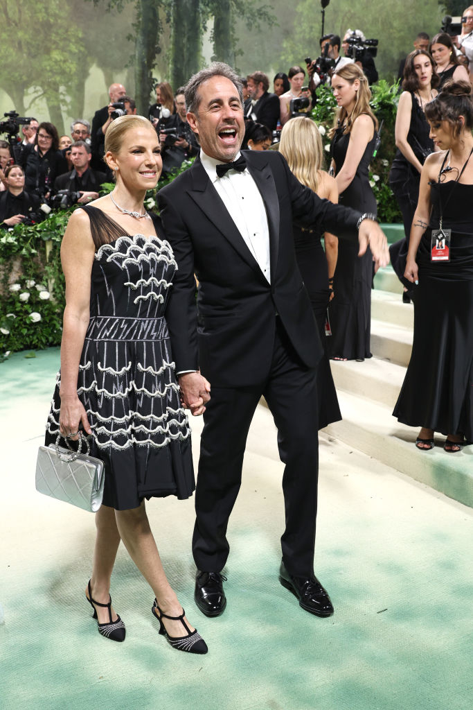 Jessica in a patterned dress and Jerry in a tuxedo, smiling and holding hands