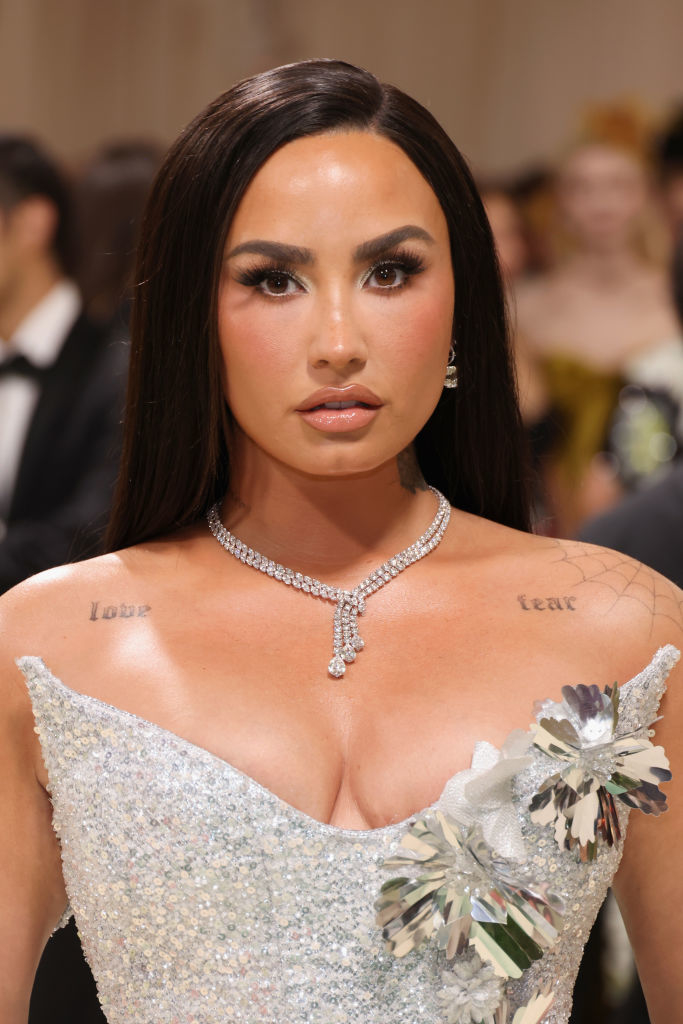 Demi Lovato in a sparkling gown with a floral accent, accessorized with a diamond necklace
