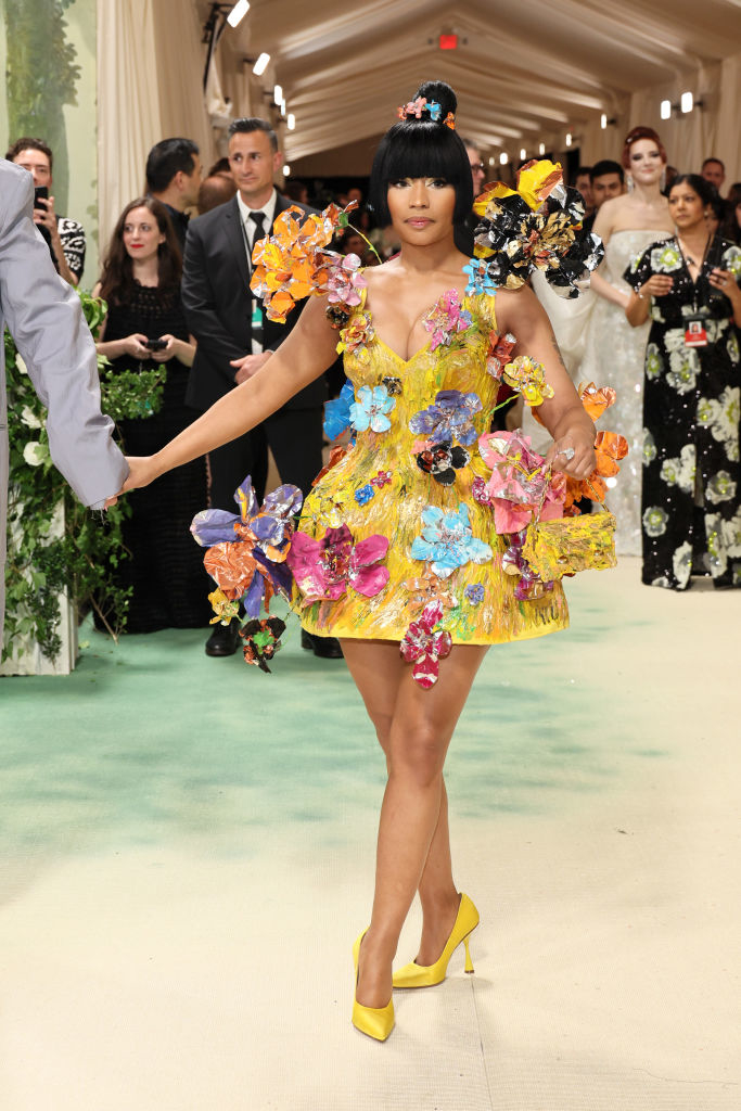 Nicki Minaj in a short floral dress with 3D flowers and butterflies, matching headdress, on a red carpet