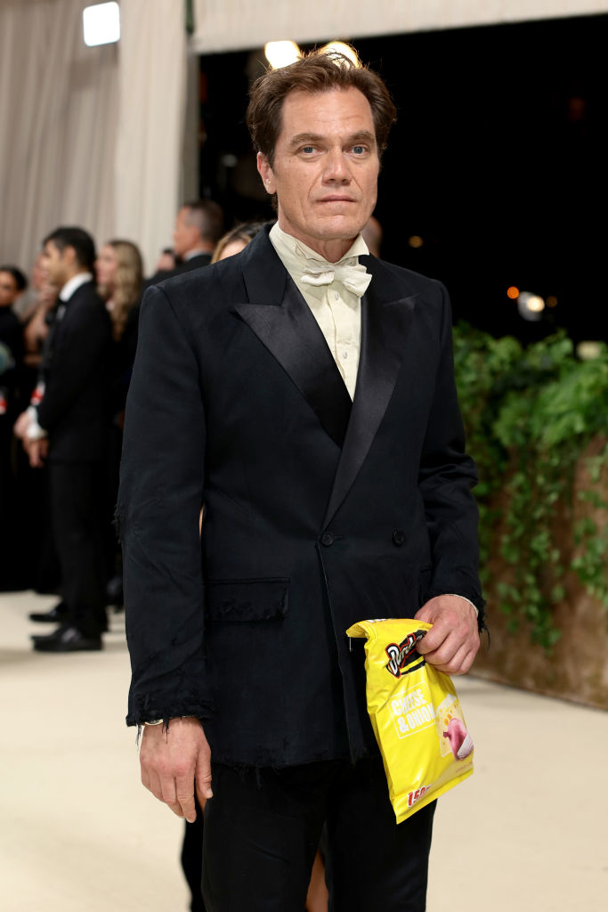 Michael Shannon at an event wearing a formal suit and holding a bag of chips