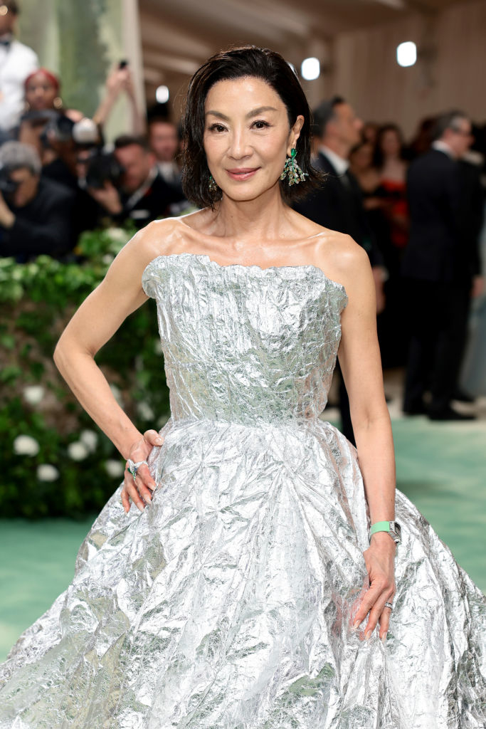 Michelle Yeoh in a reflective metallic gown with puff sleeves posing on the red carpet