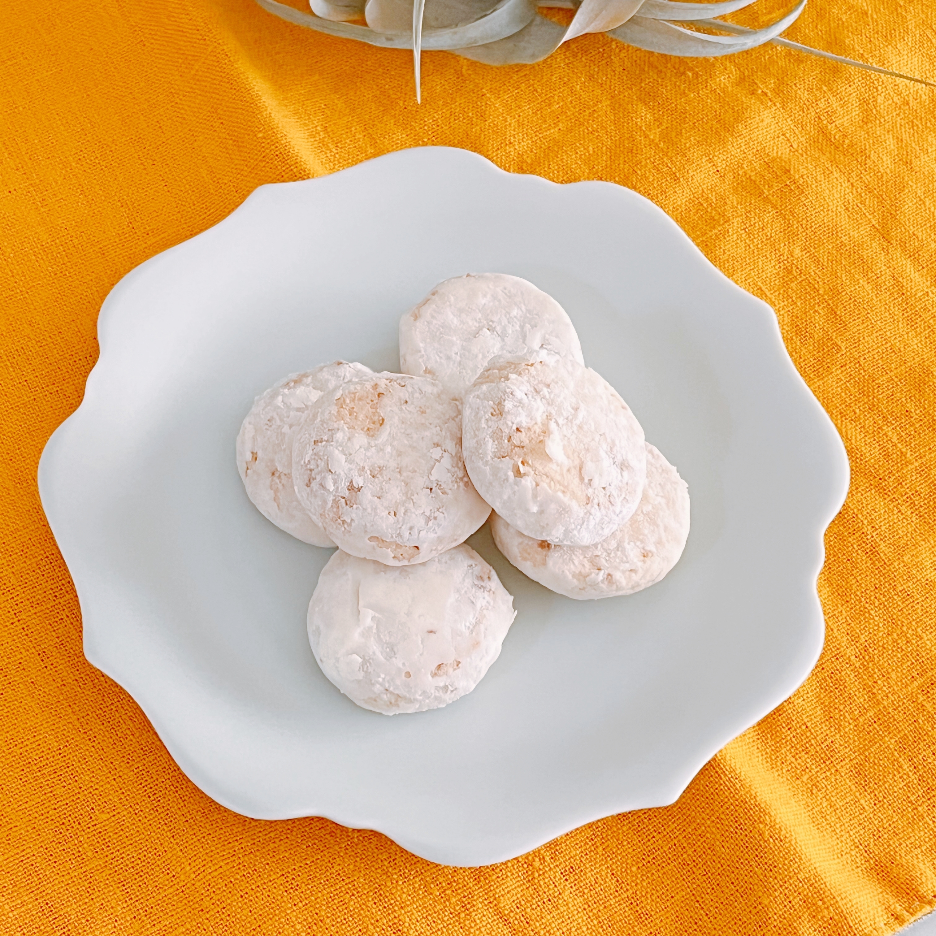 白い皿の上にあるパウダーシュガーをまぶした小さなクッキーが数個置かれています。