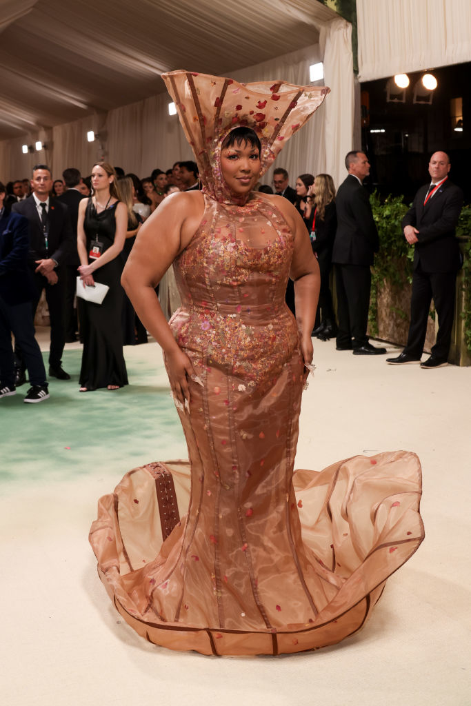 Lizzo in a beaded, figure-hugging dress with flared bottom and a matching headpiece on the Met Gala red carpet