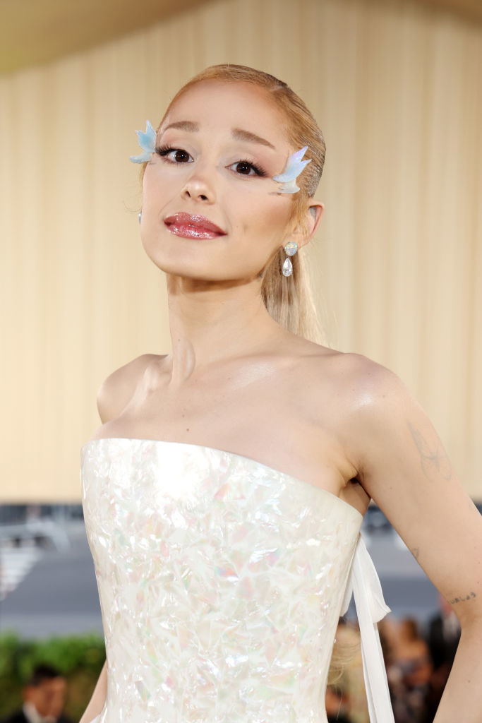 Ariana Grande wearing a strapless dress and blue butterfly decorations near her eyes