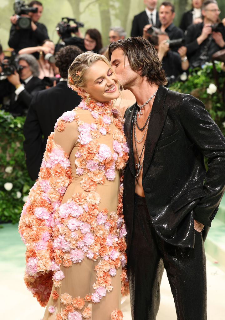 Kelsea in a floral-embellished sheer gown, Chase in a sequined suit and kissing her on the cheek