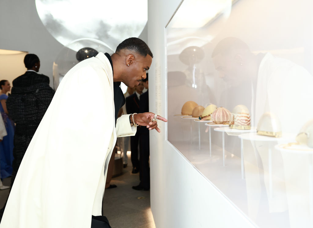 Man in elegant suit examines exhibit items closely at an event