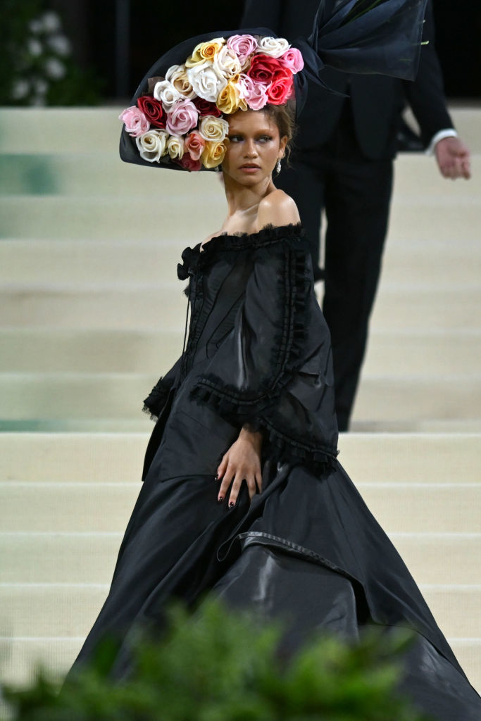 Woman in off-shoulder black gown with large flower headdress at an event