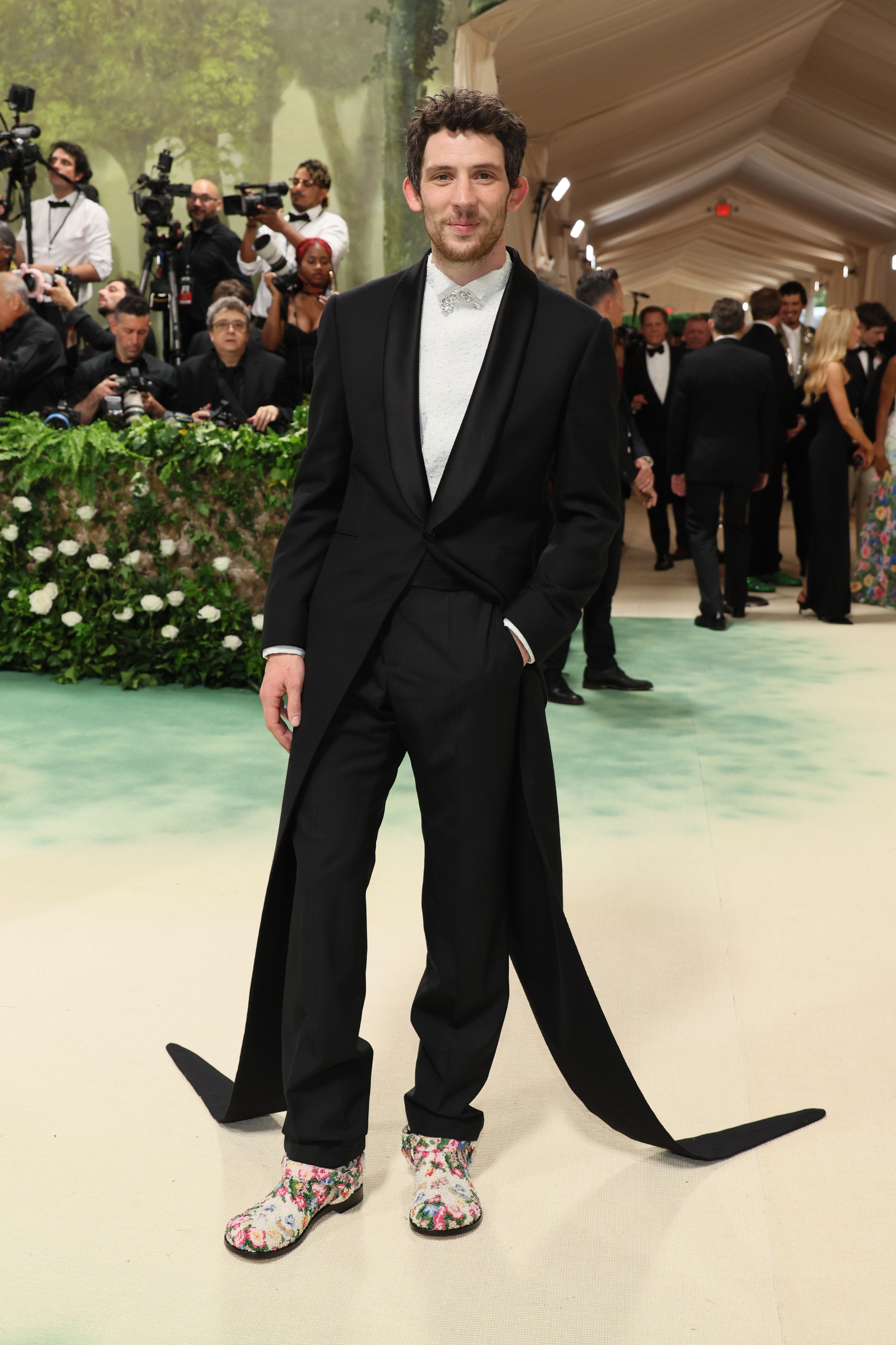 Josh O&#x27;Connor in unique black suit with long trailing ribbon and patterned shoes on event carpet