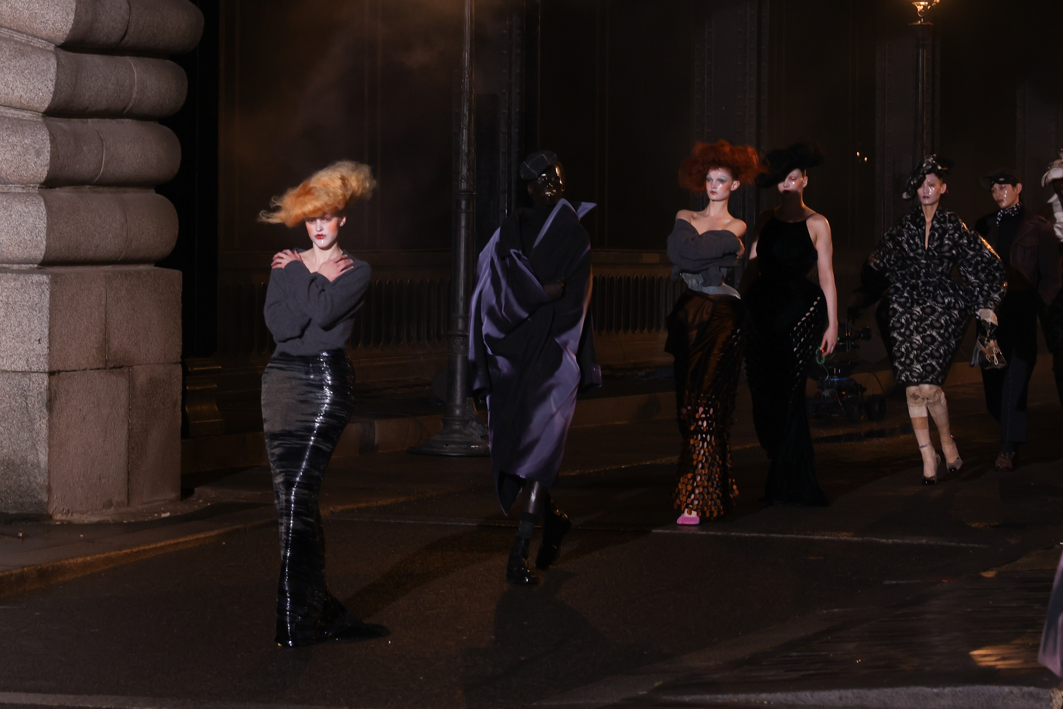 Fashion models showcasing eclectic hairstyles and unique outfits during a night event