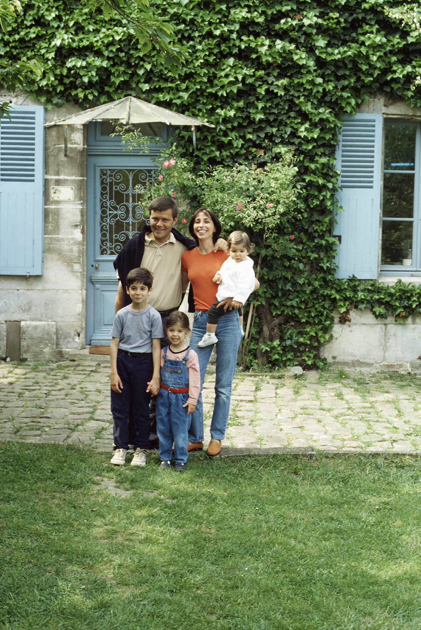 Family happily posing together in front of a house