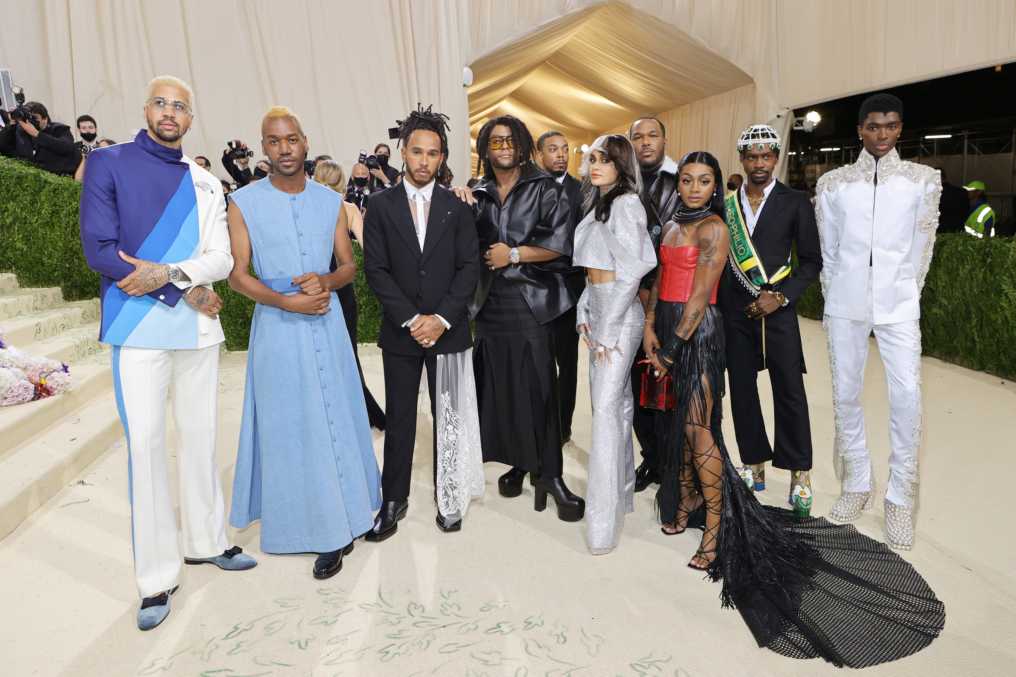 Group of people at an event wearing a variety of high-fashion outfits, some with intricate designs and textures