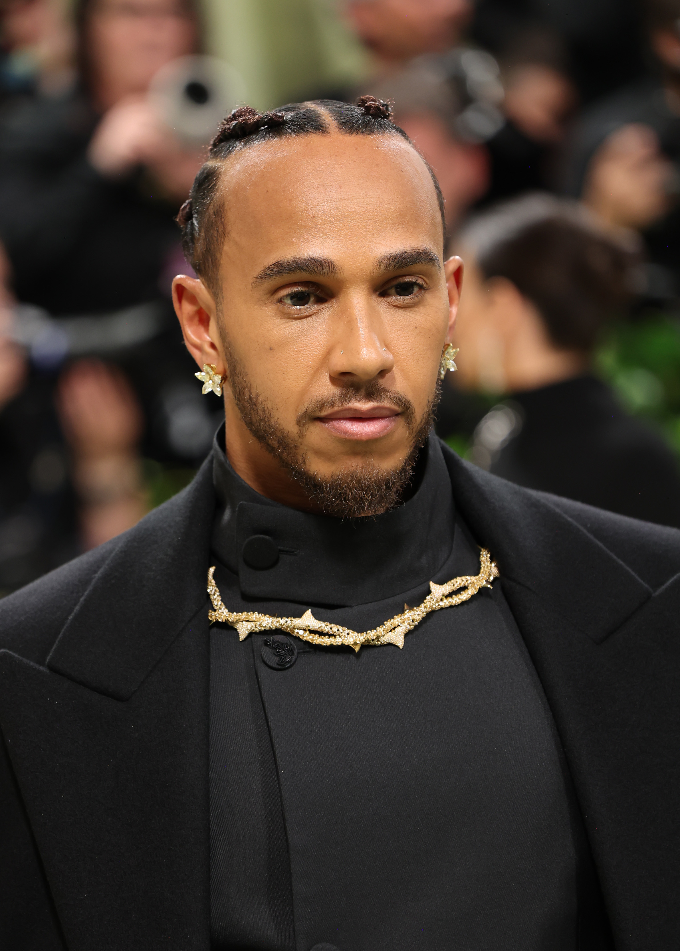 Lewis Hamilton in a black tuxedo with gold chain detail at an event