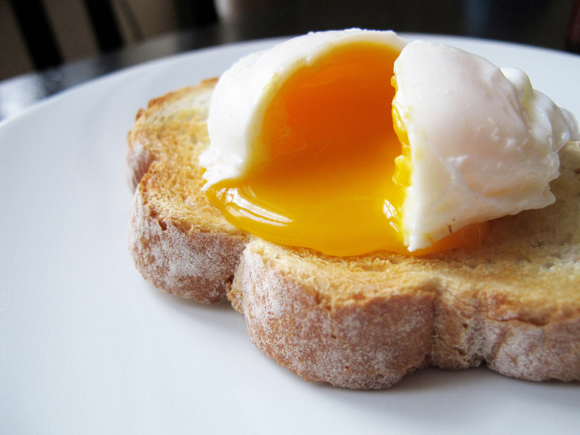 Poached egg with a runny yolk sitting atop a slice of toasted bread