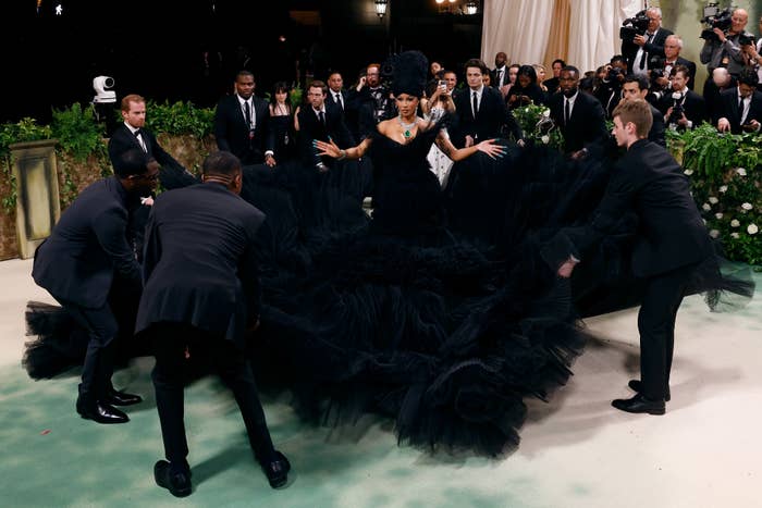 Cardi B at the Met Gala being assisted by others