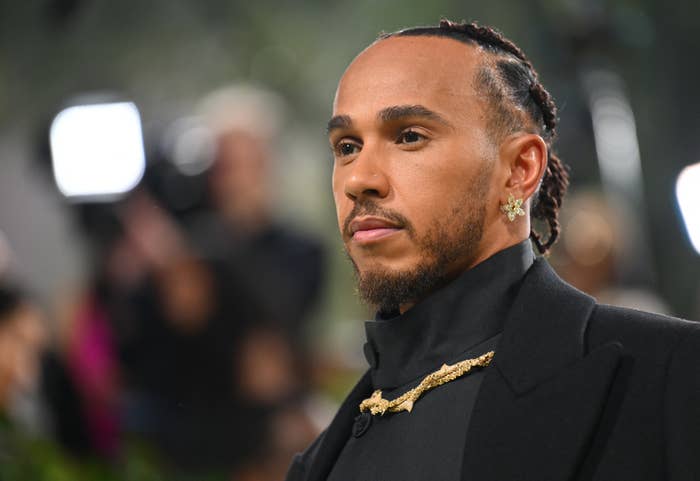Lewis Hamilton in a black tuxedo with gold chain detail at a celebrity event