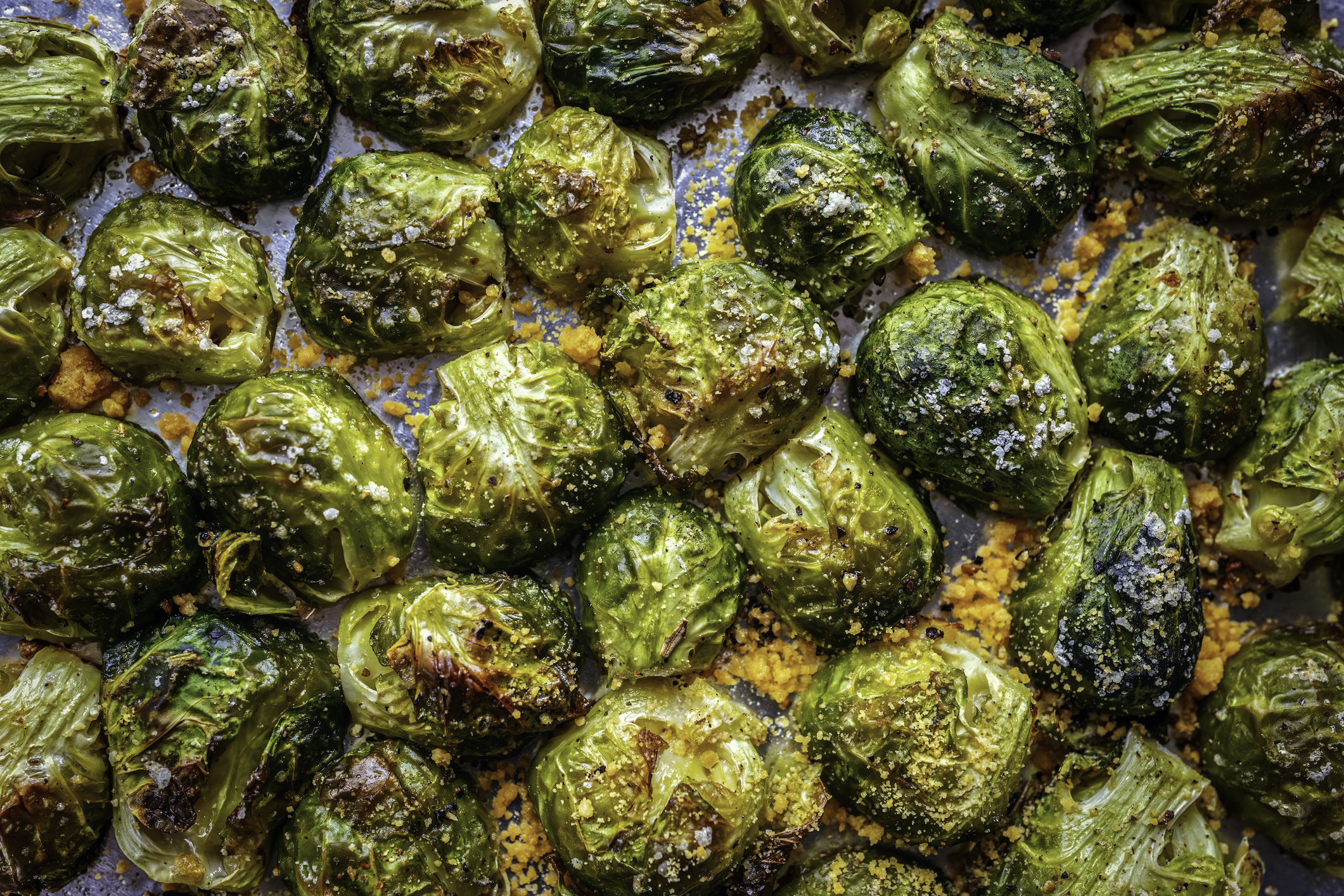 Roasted Brussels sprouts on a baking sheet, some with charred leaves, indicating crispiness