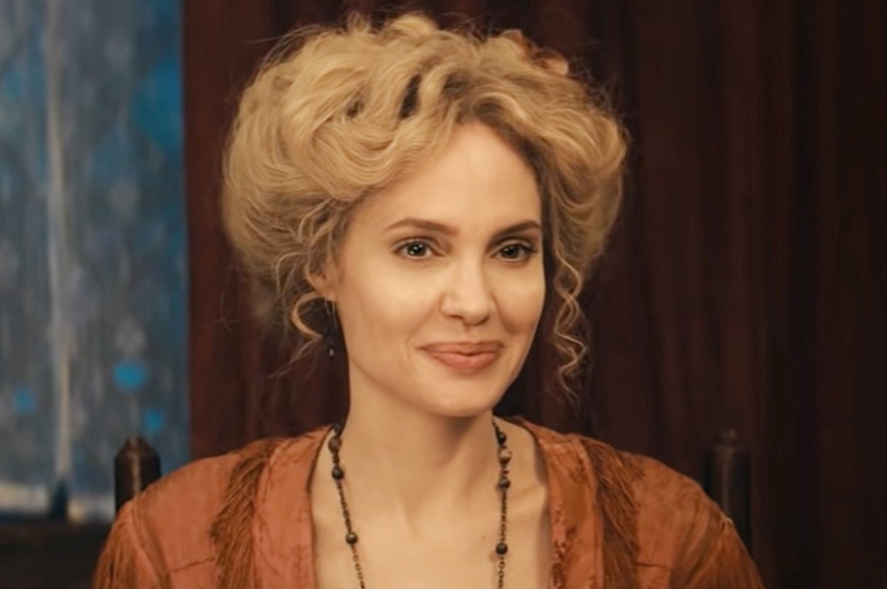 Angelina Jolie with styled updo wearing period costume, expressing amusement