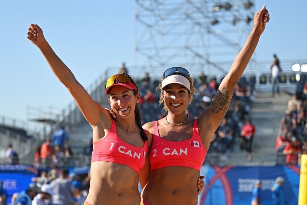 Two athletes in team uniforms with &quot;CAN&quot; on them, celebrating a victory with raised arms