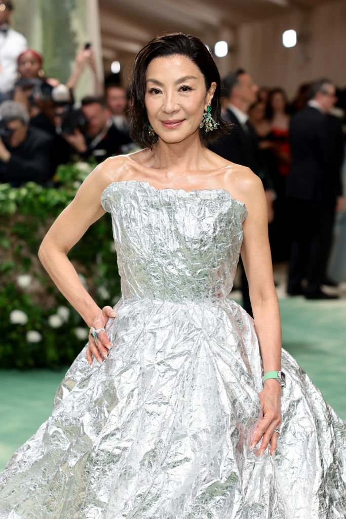 Michelle at event wearing a metallic, textured gown with hands on hips and earrings