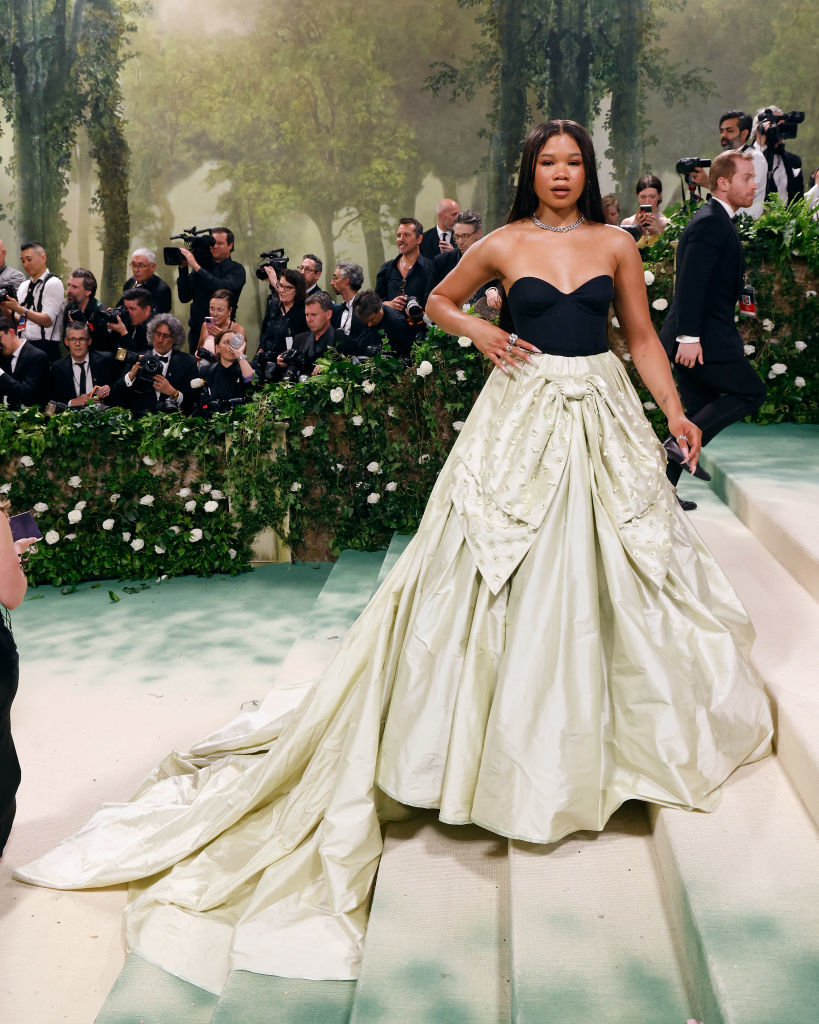 Storm in two-tone gown with a train poses at an event with photographers in the background