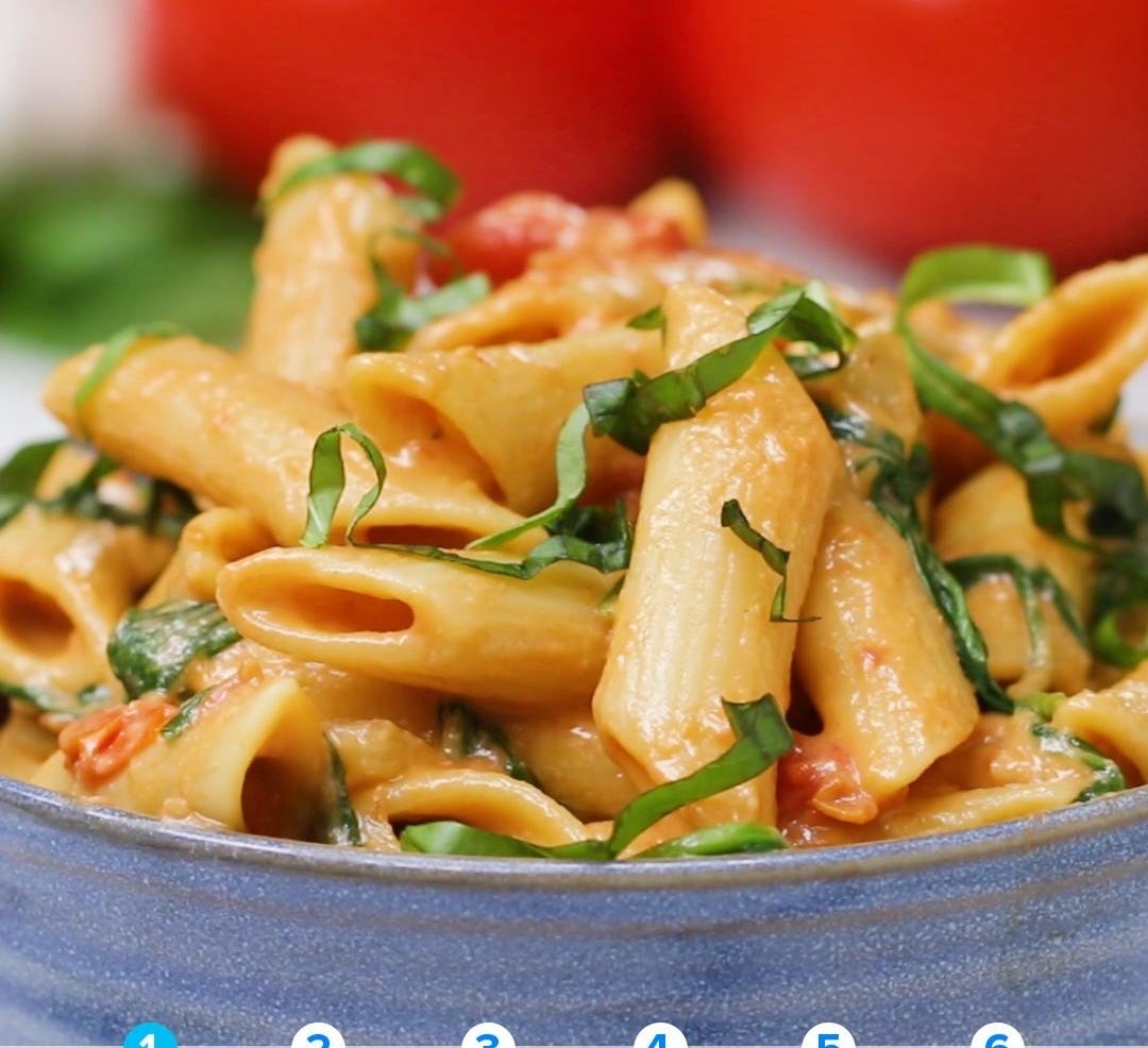 Penne pasta with tomato sauce and chopped basil served in a blue bowl, related to a tasty dish