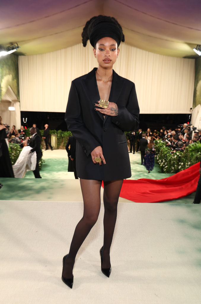 Willow in a short blazer dress and tights stands on event carpet