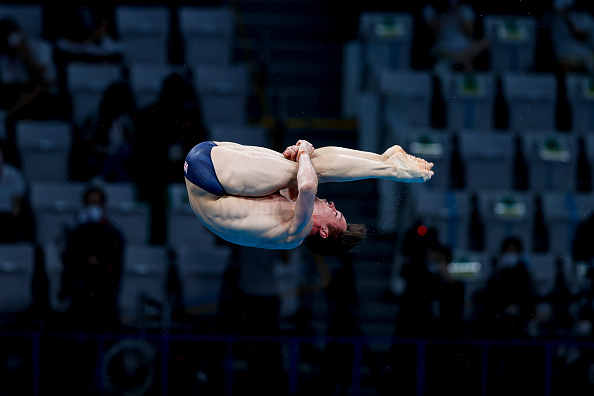 Male diver midair performing a flip at a diving competition