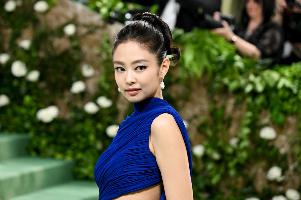 Jennie posing in an elegant blue sleeveless gown with a high neckline at a formal event