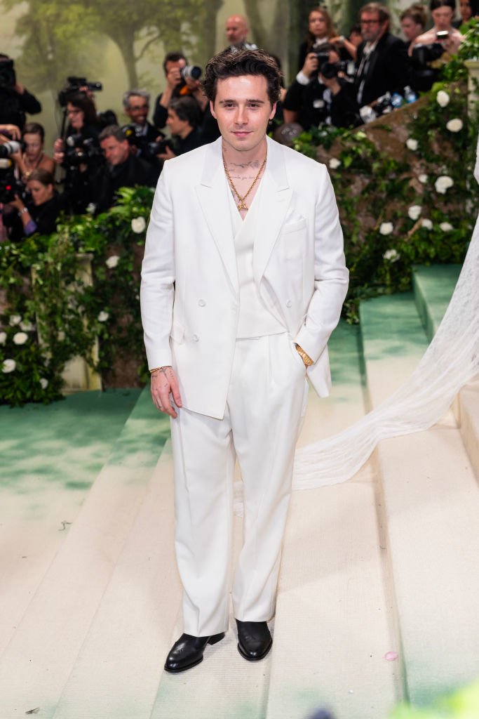 Brooklyn in a monochrome light suit at a gala event. Photographers in the background