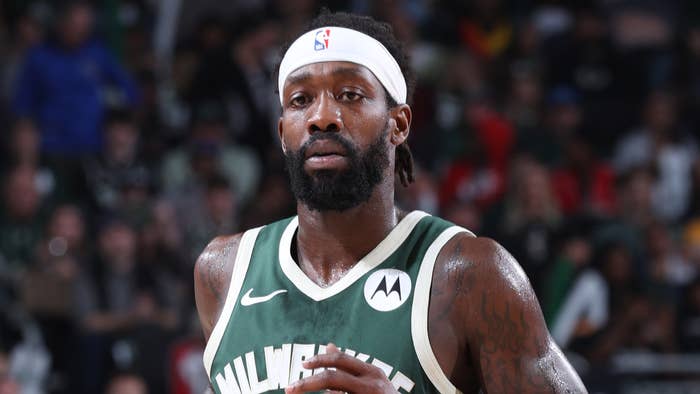 Basketball player in green jersey focused during a game, sporting a headband and beard