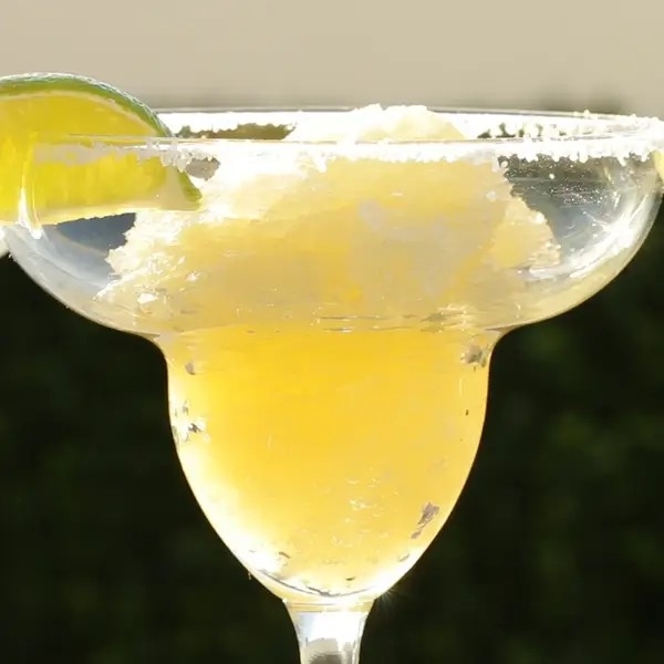 A close-up of a salt-rimmed margarita glass with a lime wedge