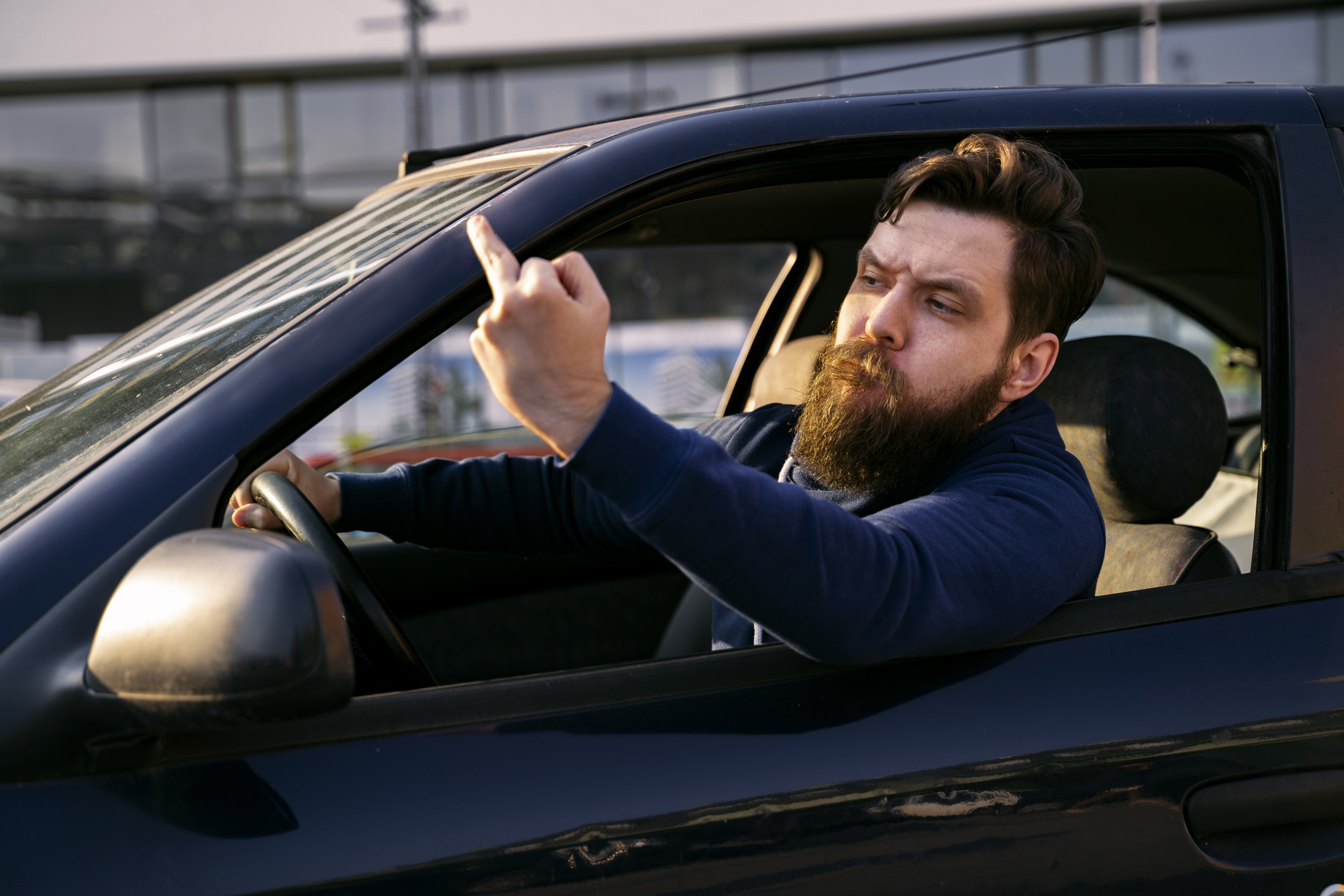 Man in vehicle making a dismissive gesture with hand