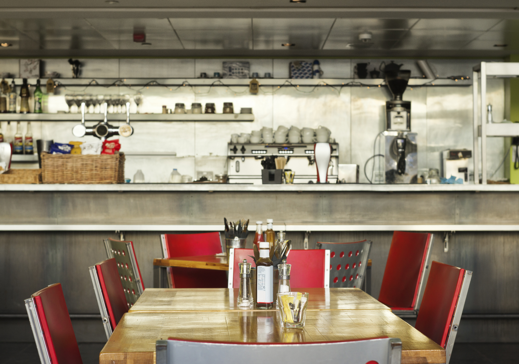 Diner interior with empty red chairs at tables and a view of the open kitchen area in the background