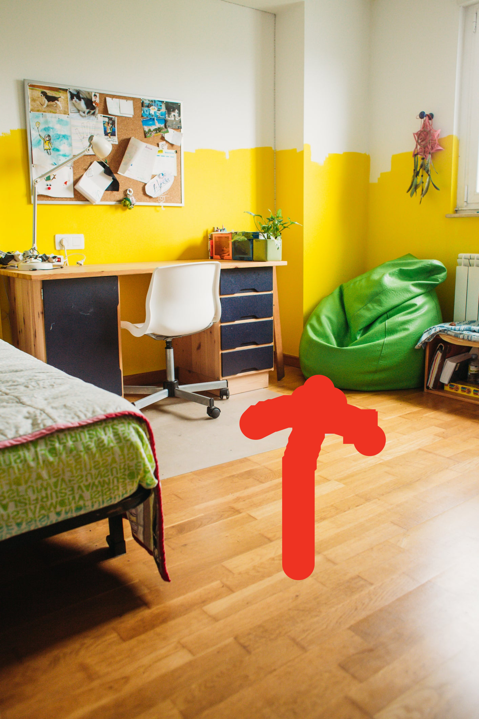 Room with bed, desk, and chair, a bulletin board full of items, and a green beanbag