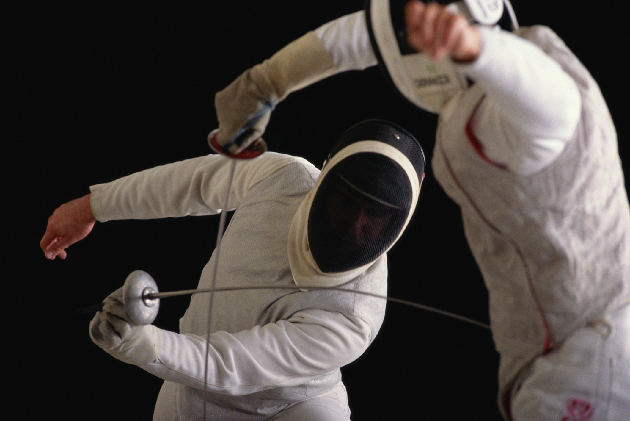 Two fencers in protective gear engaged in a match