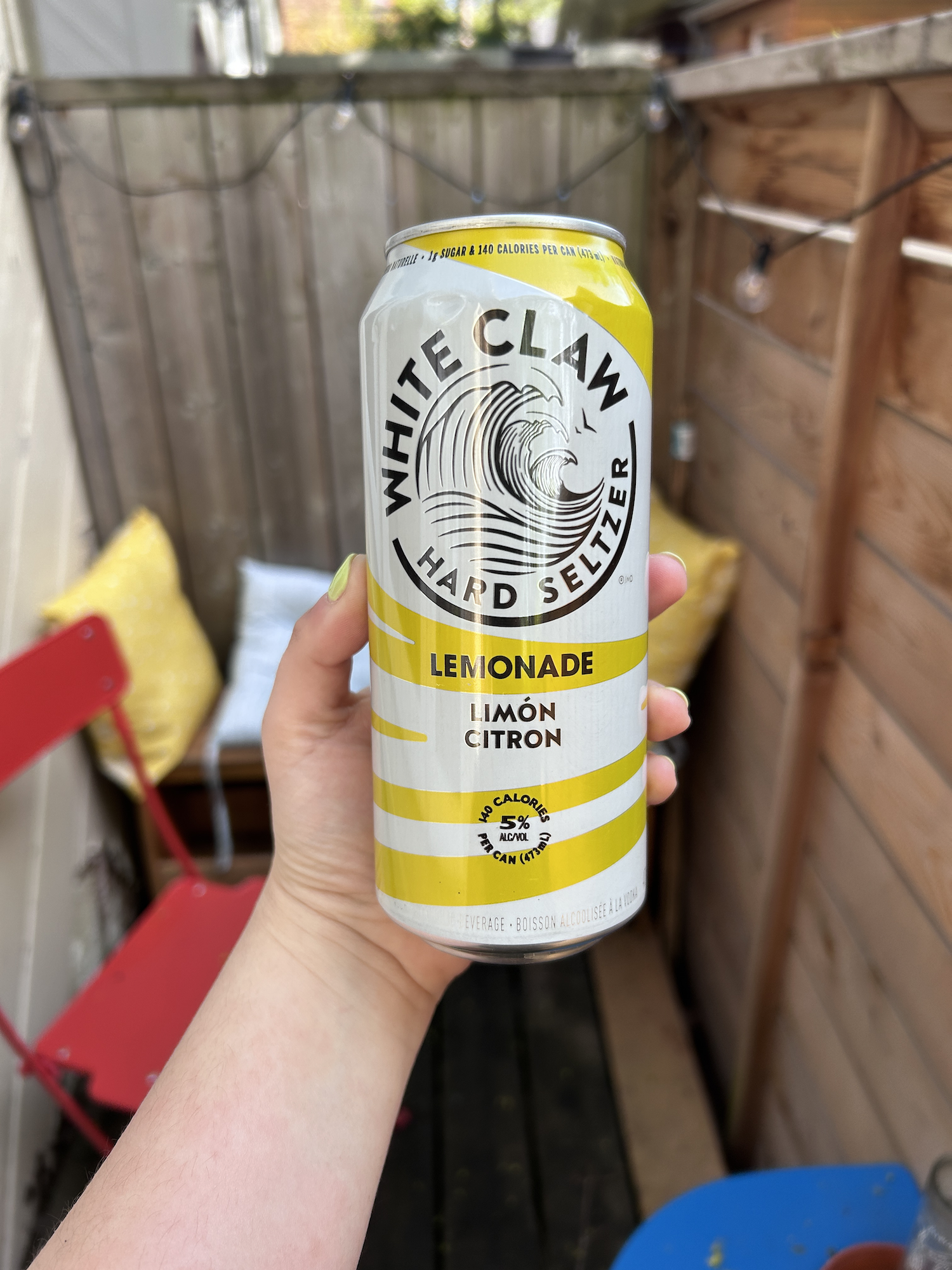 Hand holding a can of White Claw Hard Seltzer Lemonade outdoors