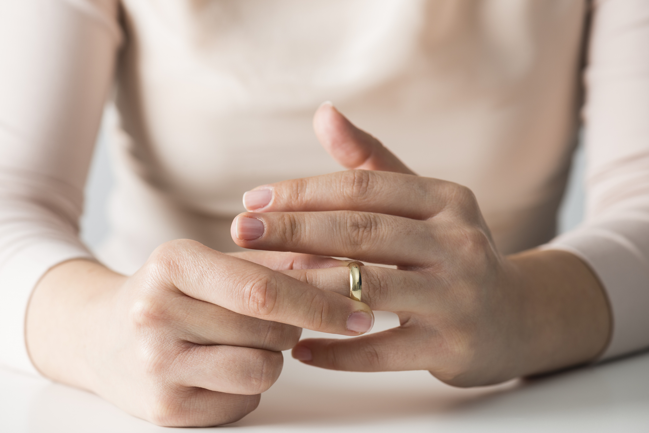 Person removing a wedding ring from ring finger