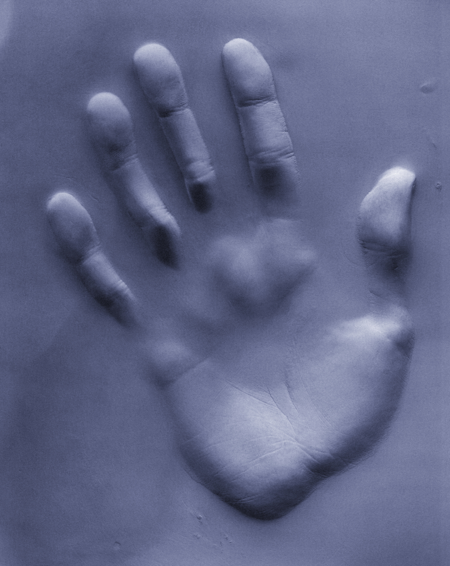 Imprint of a human hand pressed into a soft surface creating a relief effect