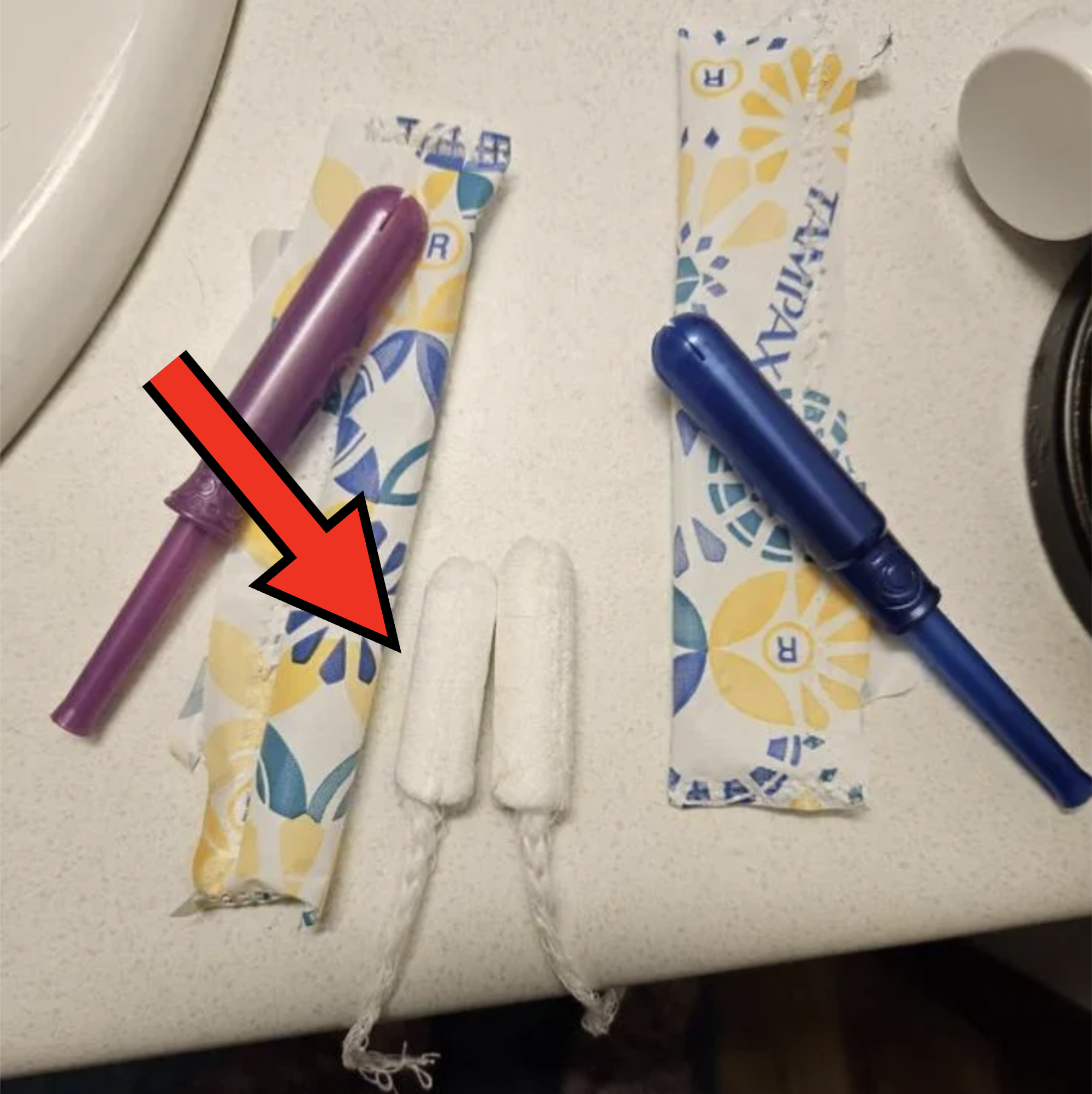 Two tampons with applicators next to two unwrapped tampons on a patterned surface