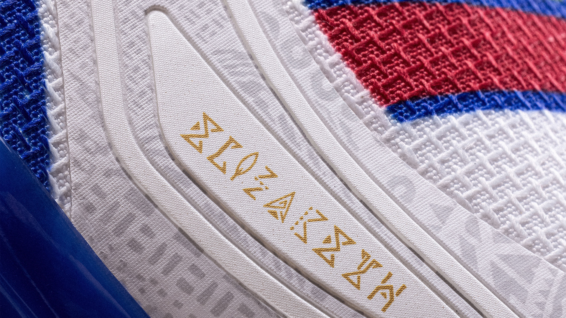 Close-up of a sneaker with textured fabric and embossed symbols on its side