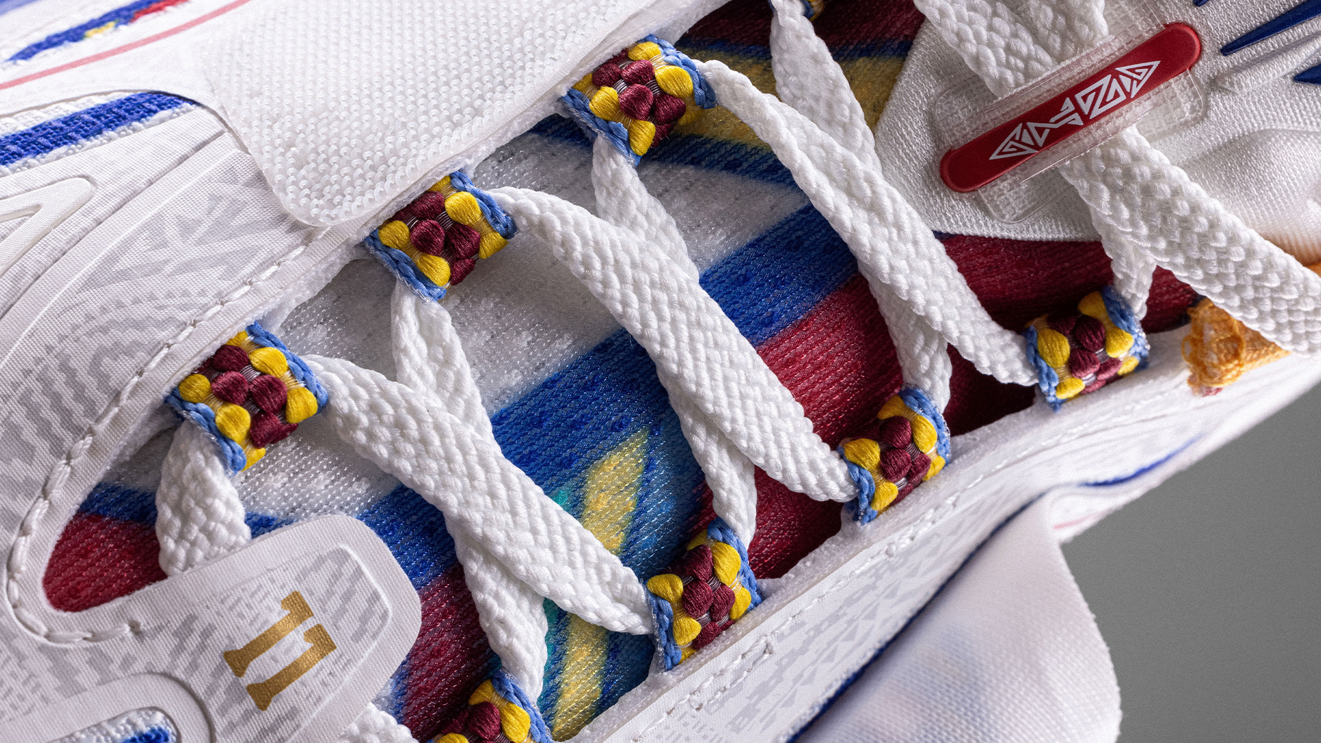 Close-up of a sneaker showcasing its intricate white lacing and multicolored fabric