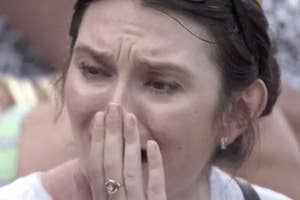 Emotional woman covering mouth with hand, appears to be crying or in shock