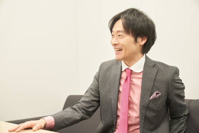 スーツを着た笑顔の男性がオフィスで会話しています。